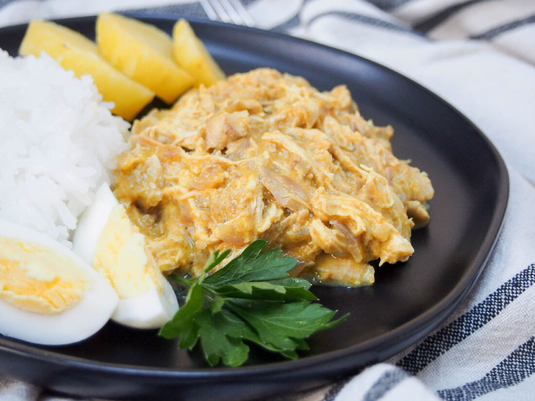 Aji de gallina (Peruvian chicken stew) close up on plate with rice, potato and egg sides