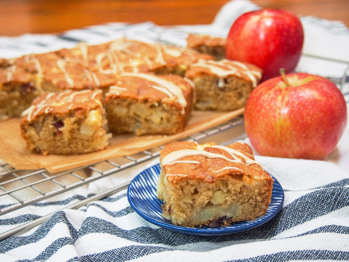 small plate with a piecxe of apple snack cake in front of more slices and apples