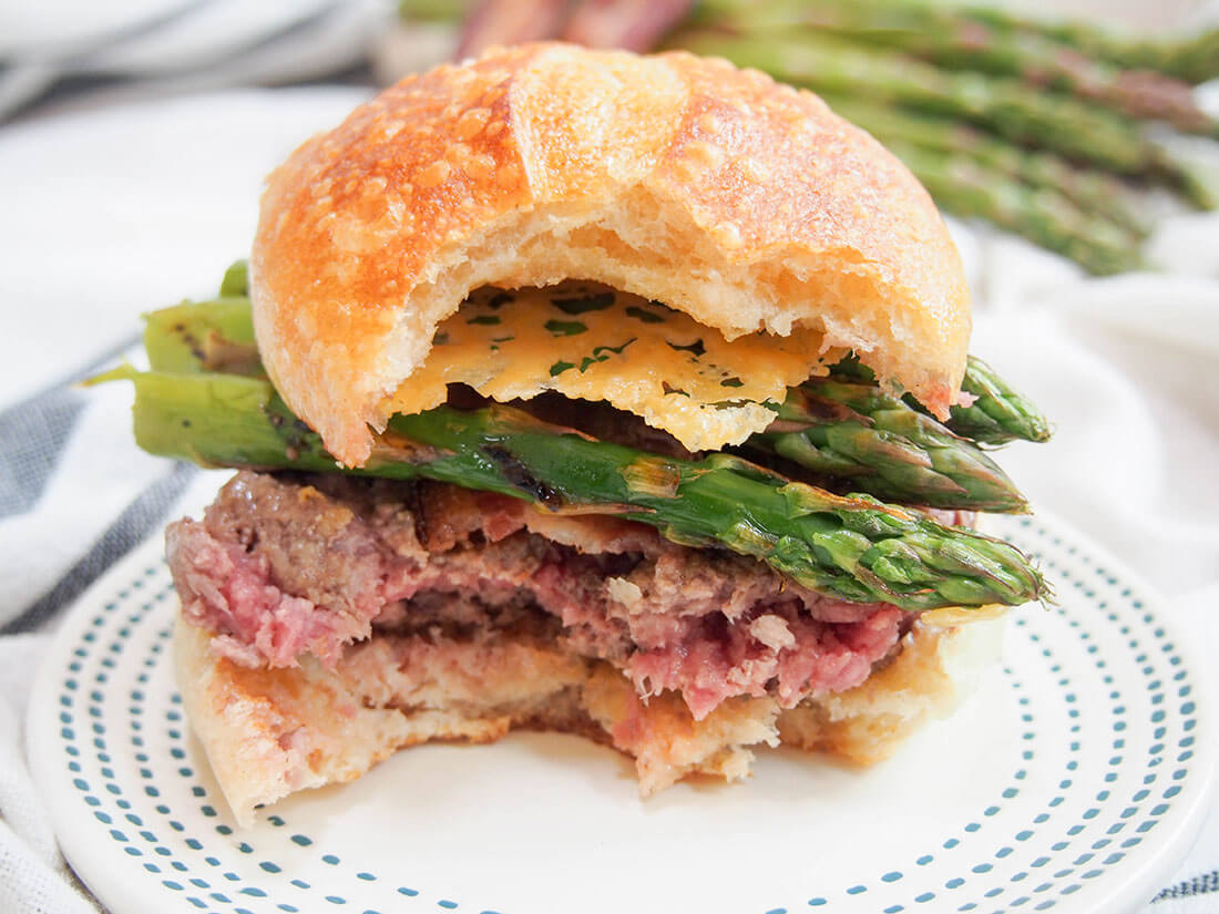 Asparagus parmesan burger with parmesan crisps with bites taken from it