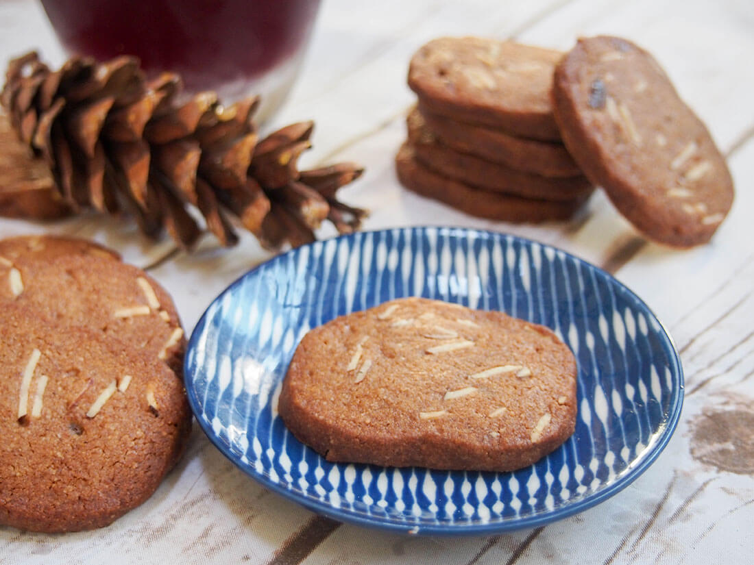 Brunkager cookie on small plate with stack behind and more to side