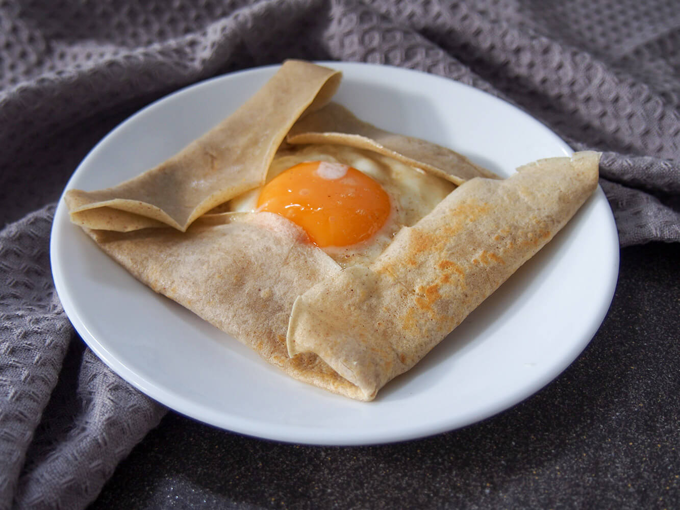 French buckwheat crepe filled with cheese ham and egg on plate