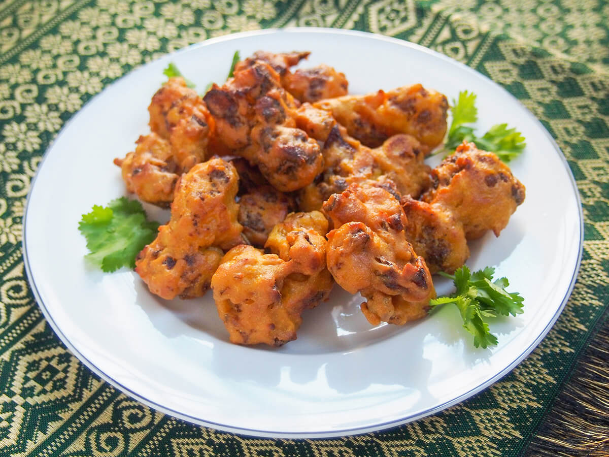 plate of cauliflower pakora on green and gold cloth