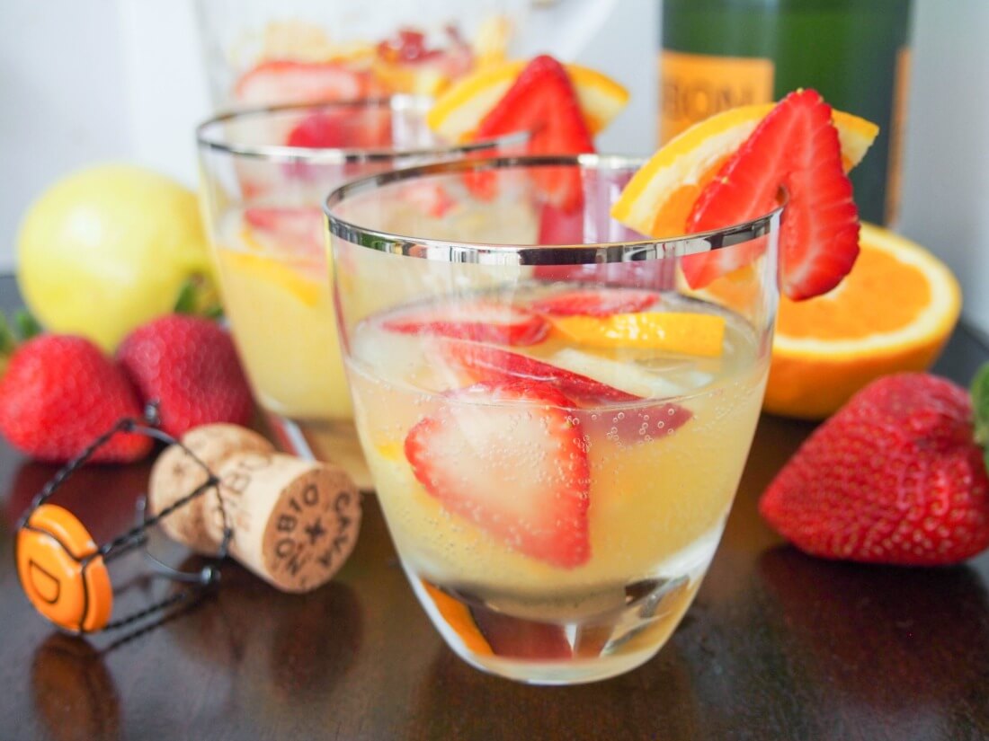 two glasses of cava sangria with fruit and cork around glasses