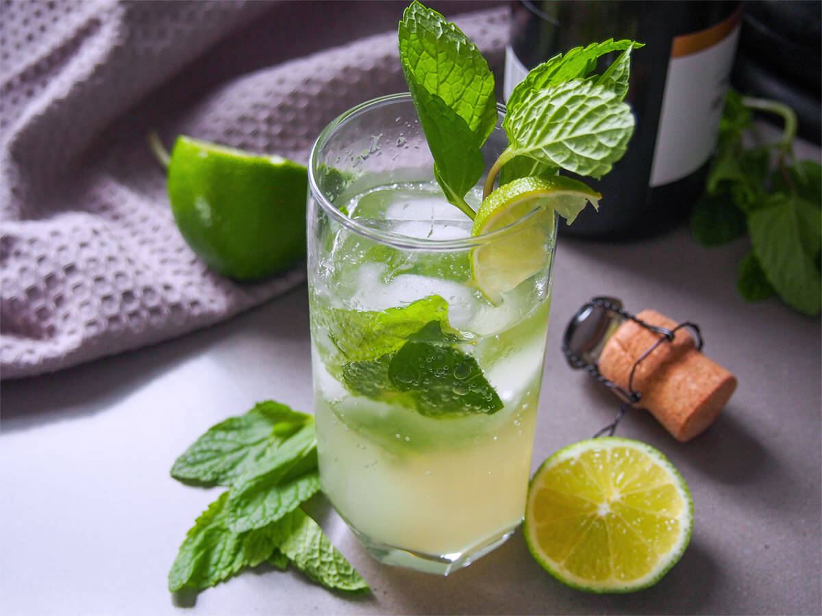 glass of champagne mojito with lime and cork to side of glass