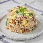 stach of chashu chahan, Japanese fried rice, showing pieces of chashu, egg and peas amongst rice.