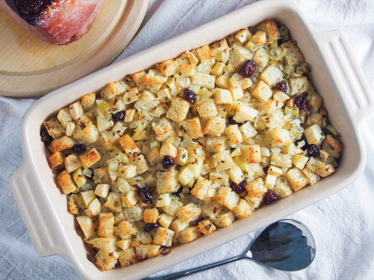 baking dish filled with cranberry apple stuffing with spoon below dish