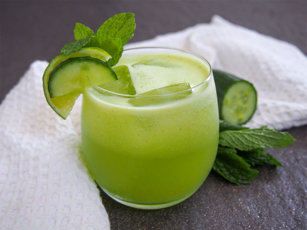 glass of cucumber agua fresca garnished with mint, cucumber and lime slices