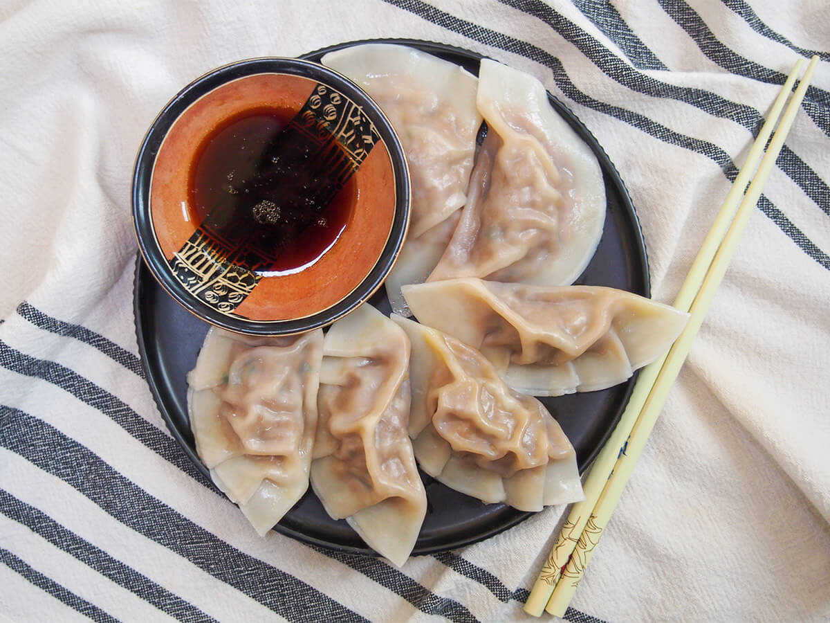 overhead view of plate of cumin lamb dumplings with chopsticks to side