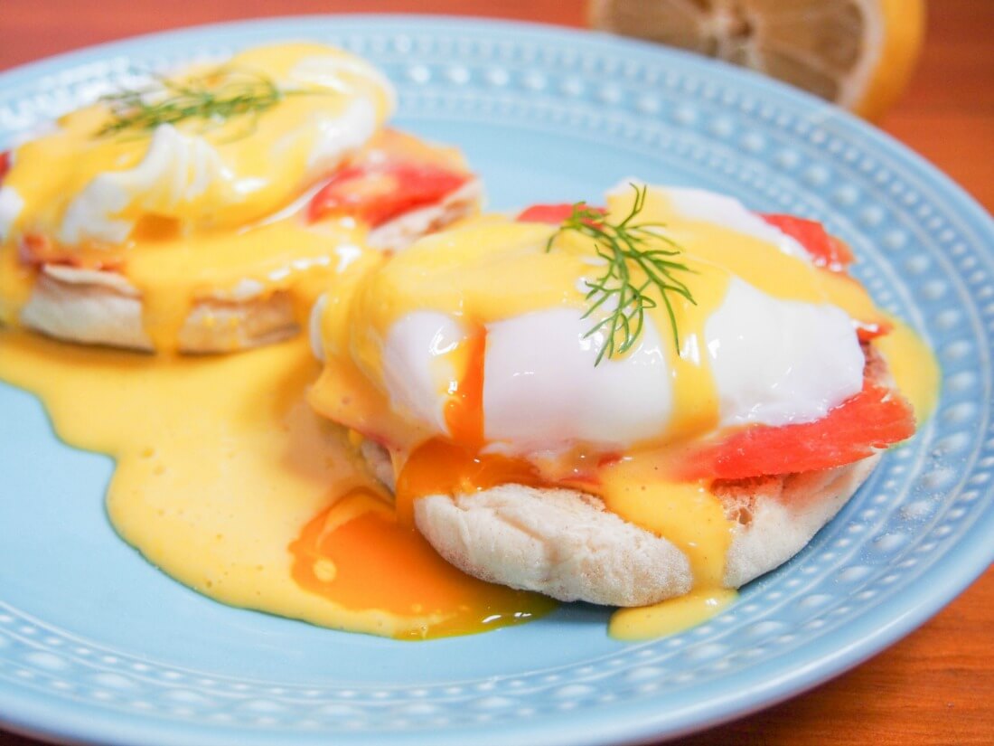 Eggs Royale (smoked salmon eggs Benedict) on plate with egg yolk cut and oozing into sauce