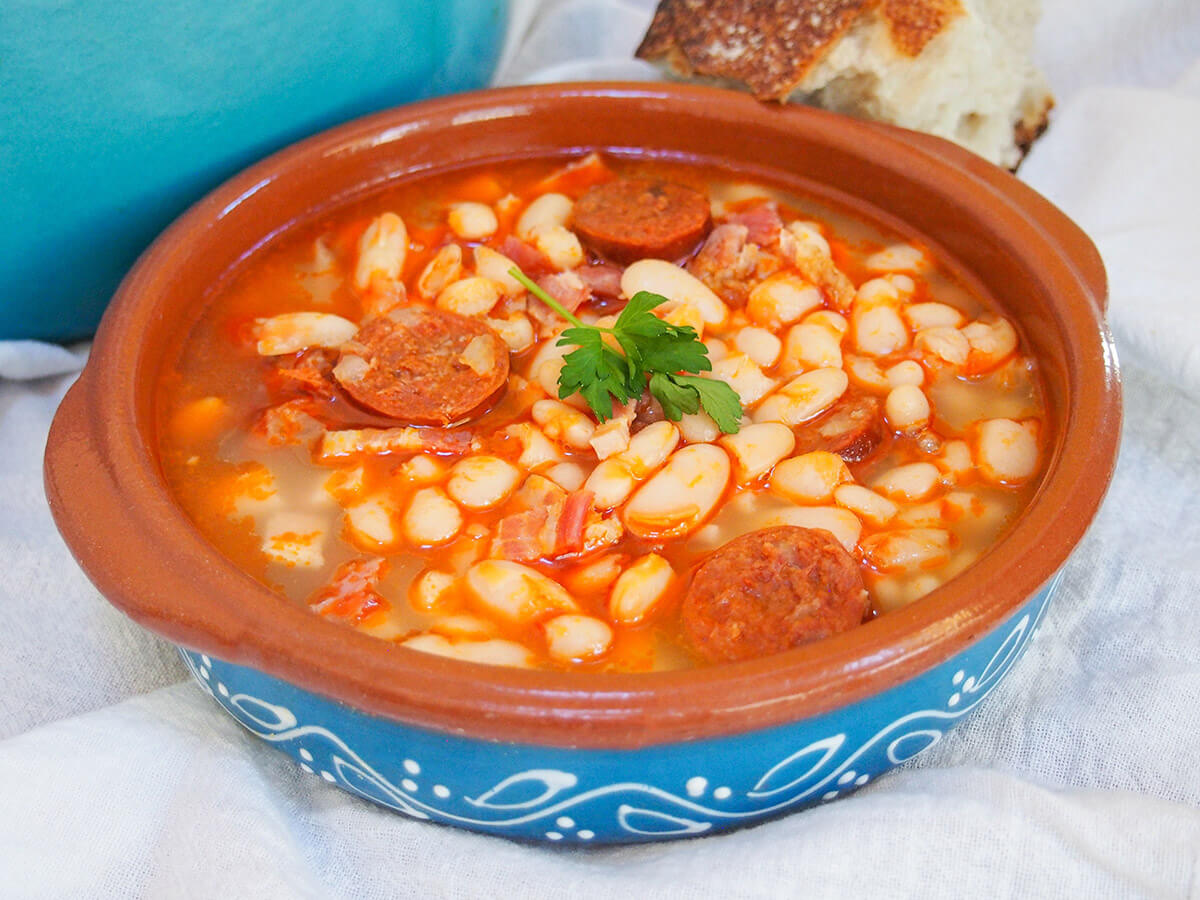 bowl of fabada asturiana with bread resting on back on bowl