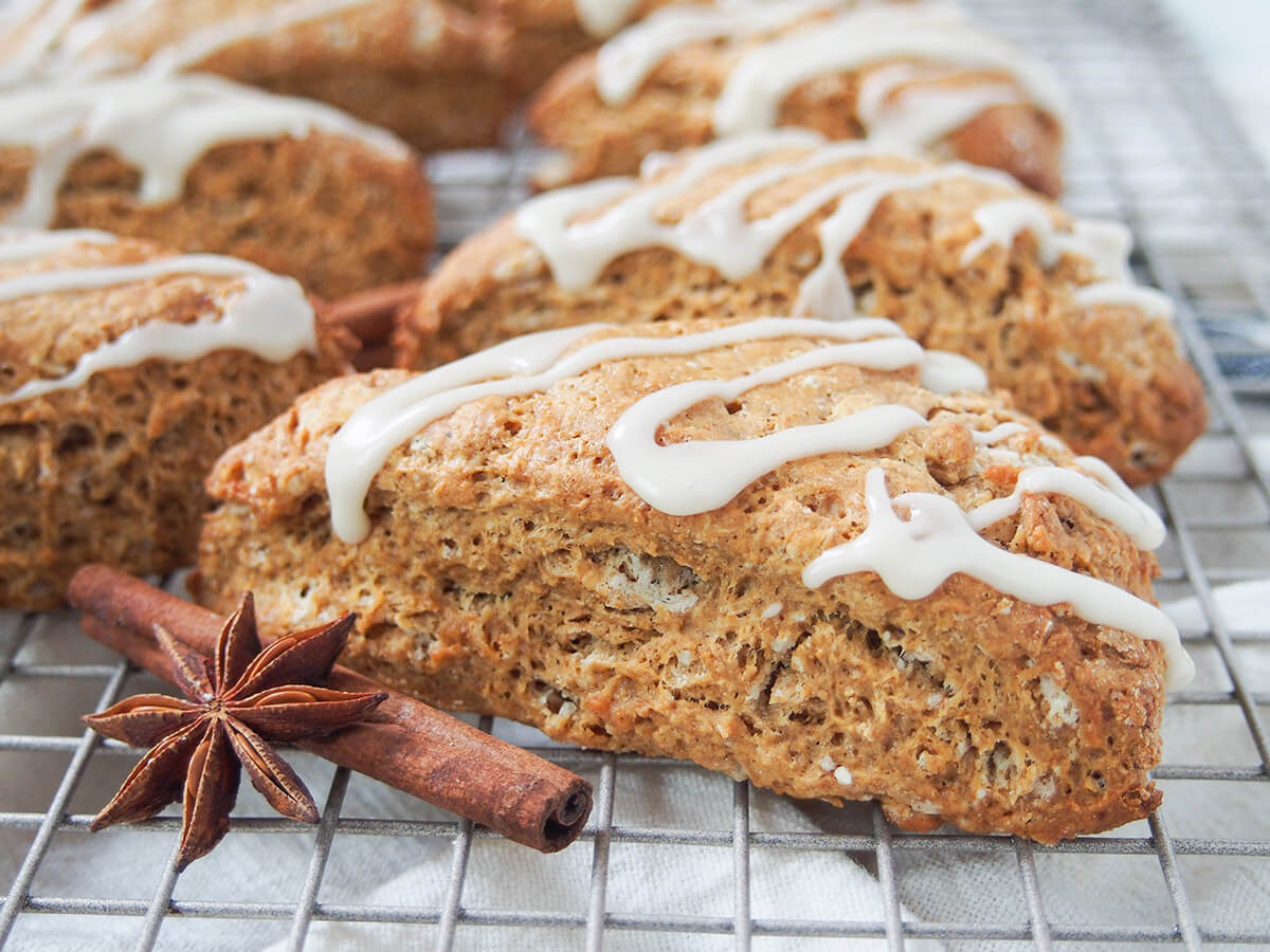 side view of a gingerbread scone with whole spices to side and more scones behind.