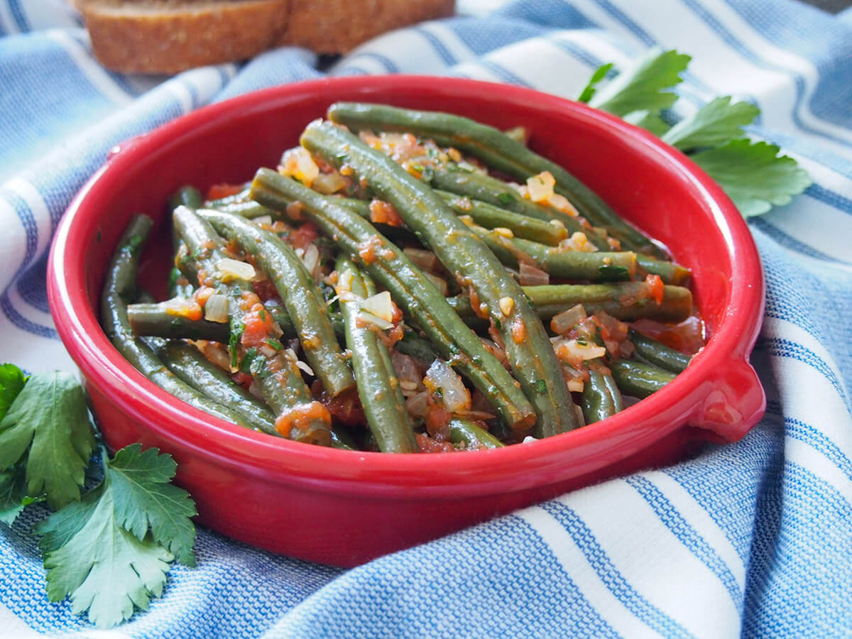 bowl of Greek green beans fasolakia on blue cloth