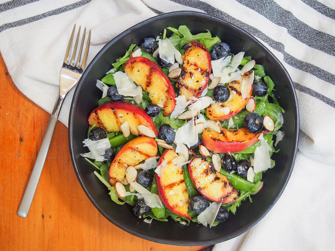 grilled peach salad in bowl with fork to side