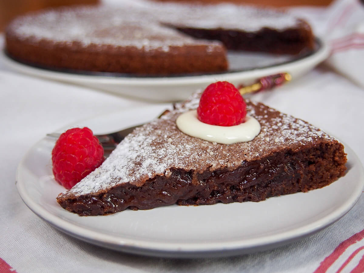 slice of kladdkaka Swedish sticky chocolate cake on plate garnished with raspberries