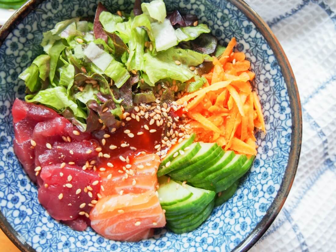 Korean sashimi rice bowl with sashimi to bottom and salad top and side