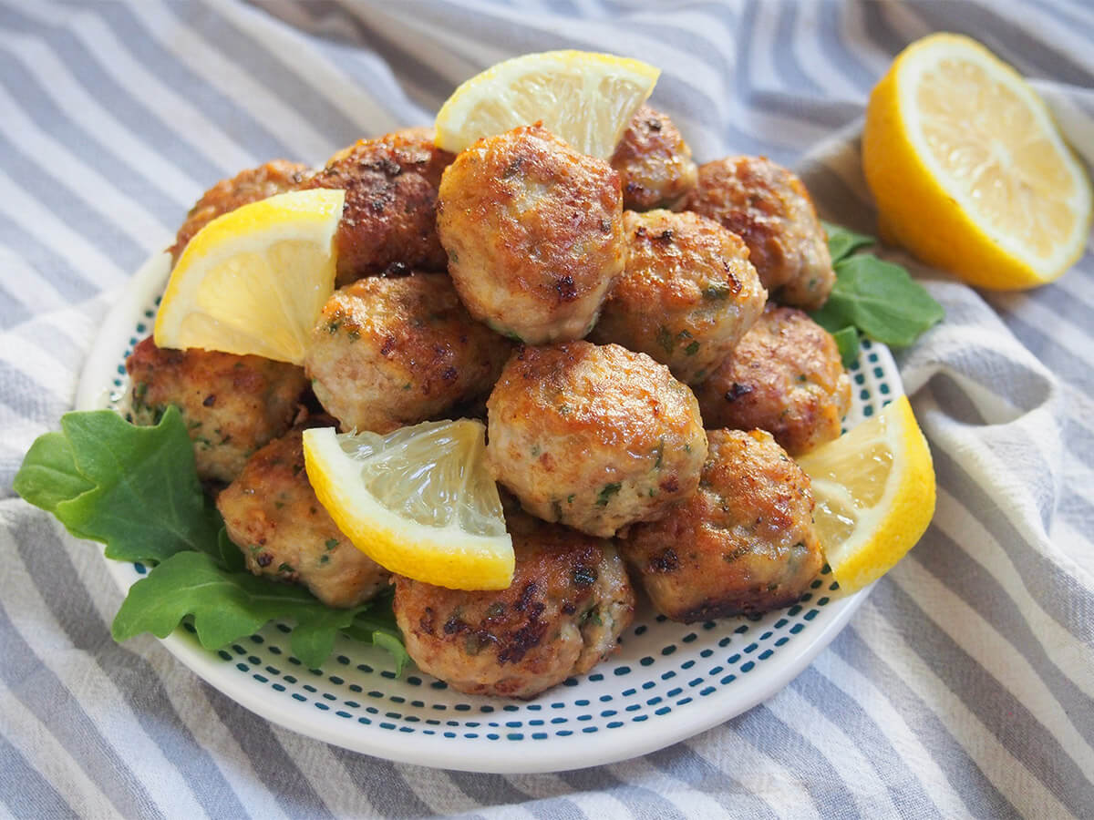 plate of lemon pork meatballs with part lemon behind