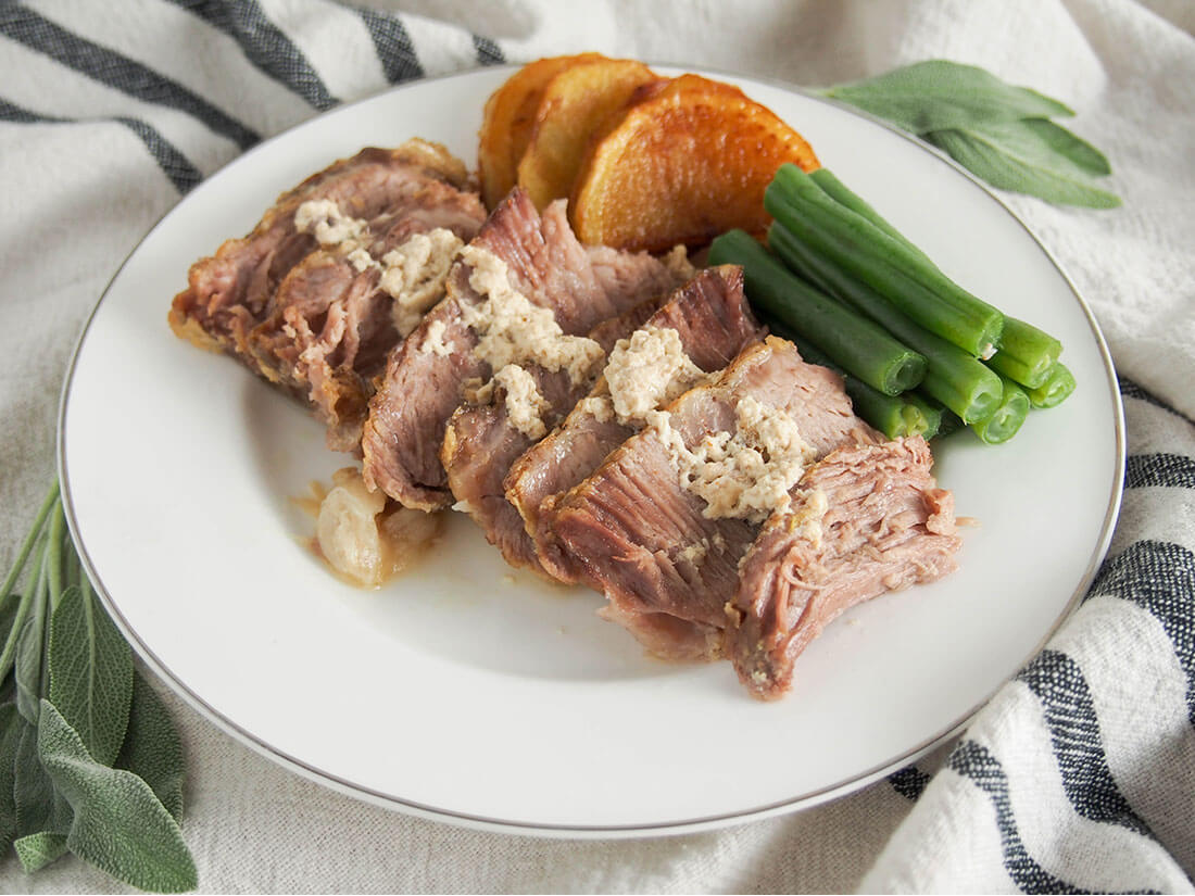 Milk-braised pork (maiale al latte) on plate with green beans and potatoes as sides