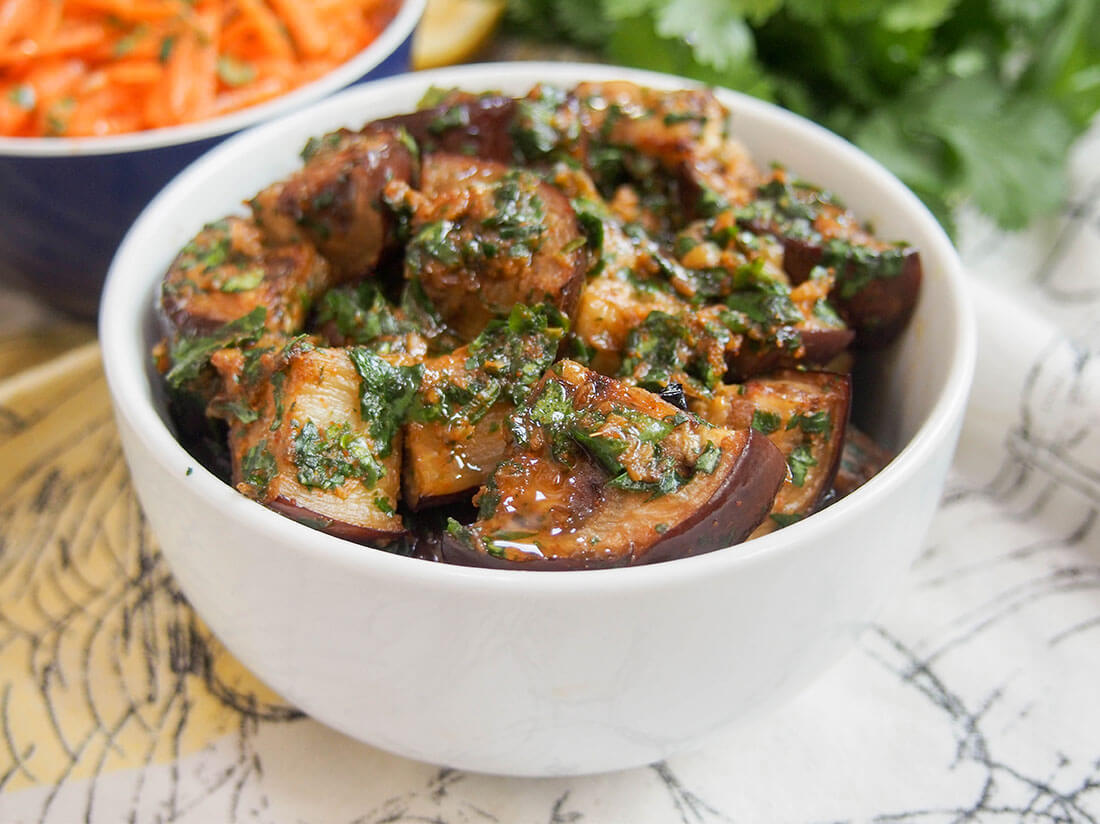 Moroccan eggplant with chermoula in bowl with carrot salad behind