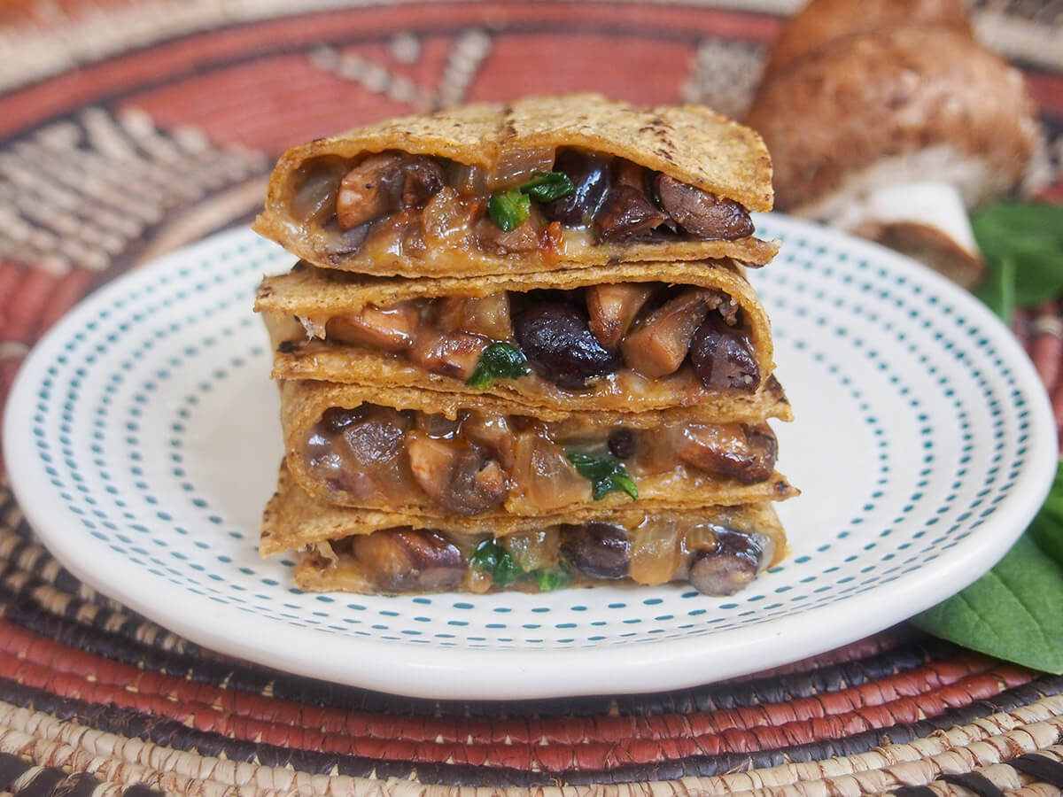 stack of pieces of mushroom quesadilla with mushroom behind plate