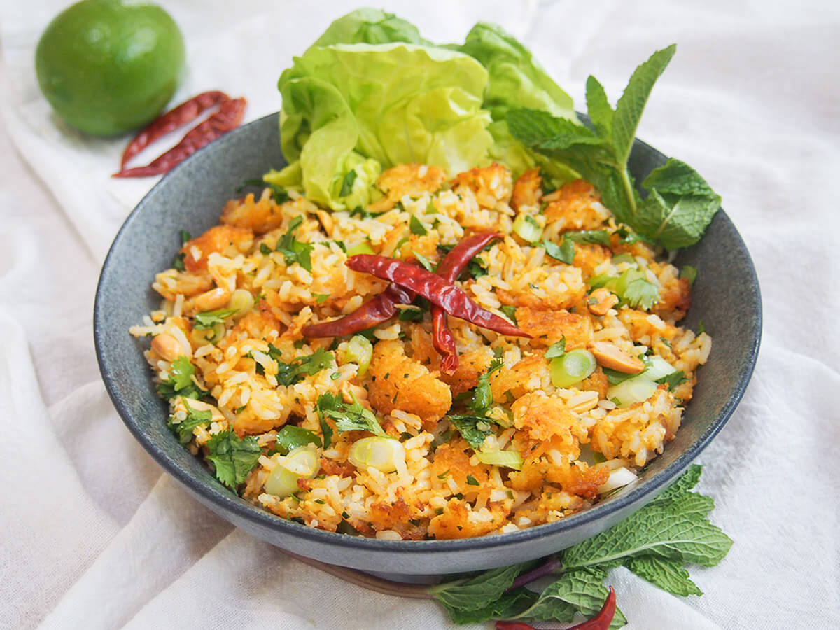 bowl of nam khao Lao crispy rice salad with lime and chilis behind bowl