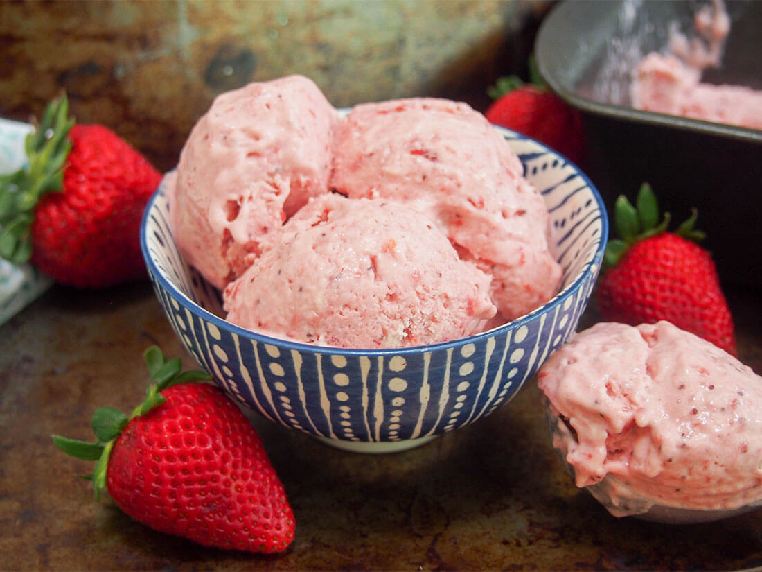 No churn roasted strawberry ice cream in bowl with scoop to side