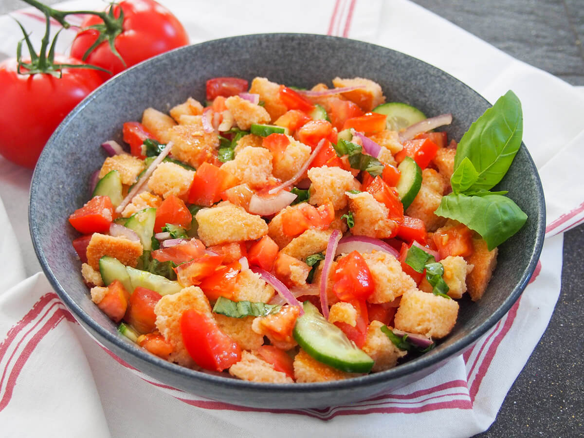 bowl of panzanella salad viewed from side with basil garnish