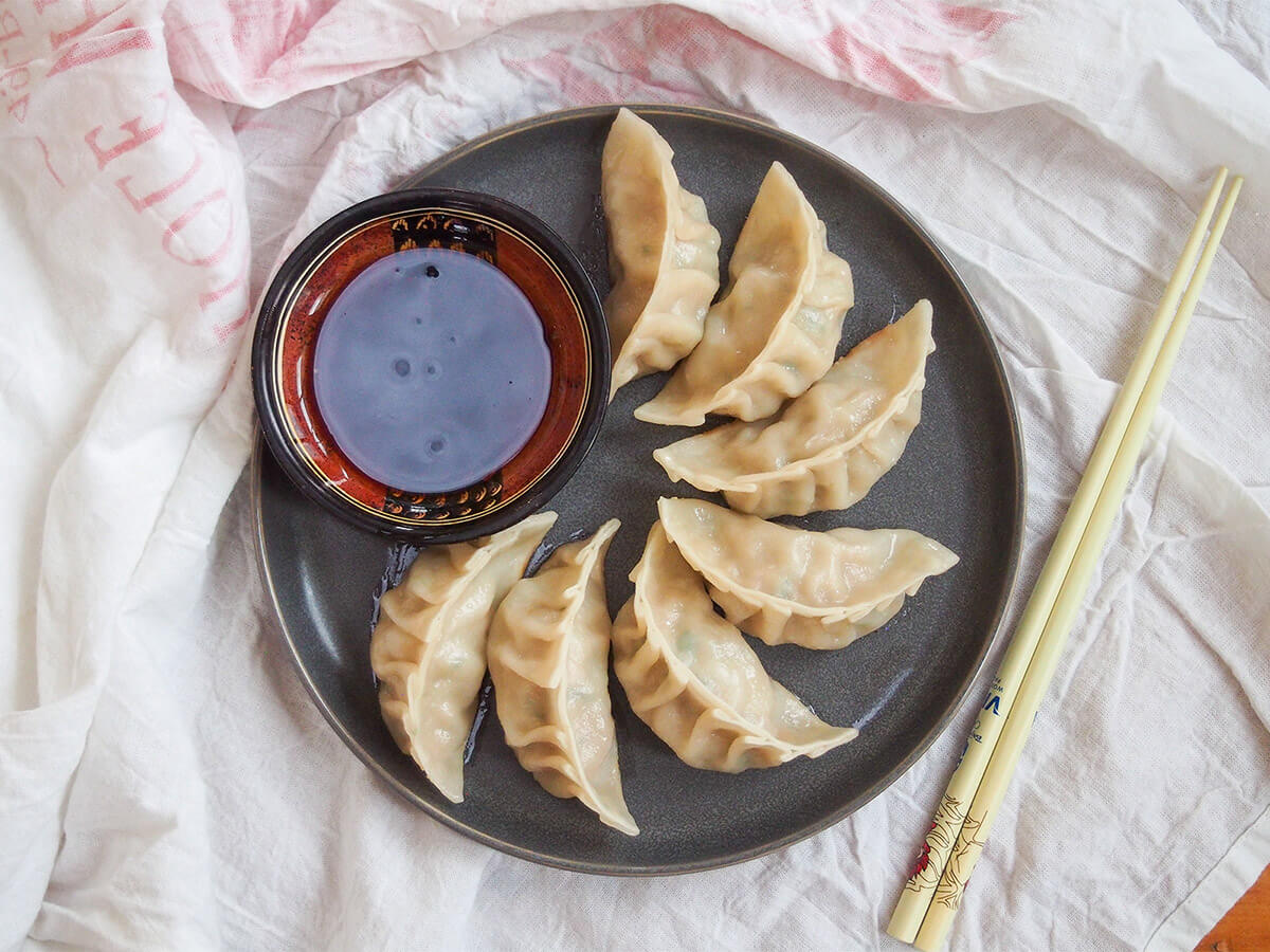 pork and cabbage dumplings on plate with chopsticks to side of plate