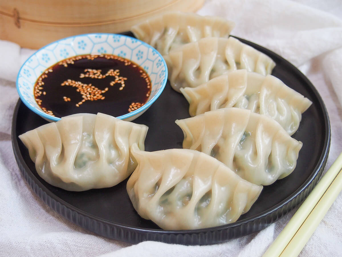 plate of pork and chive dumplings with dipping sauce to back of plate