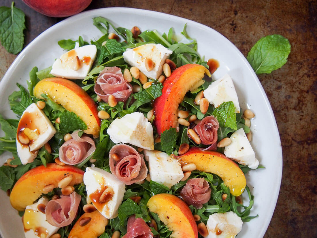 partial overhead shot of plate of prosciutto salad with peach and mozzarella