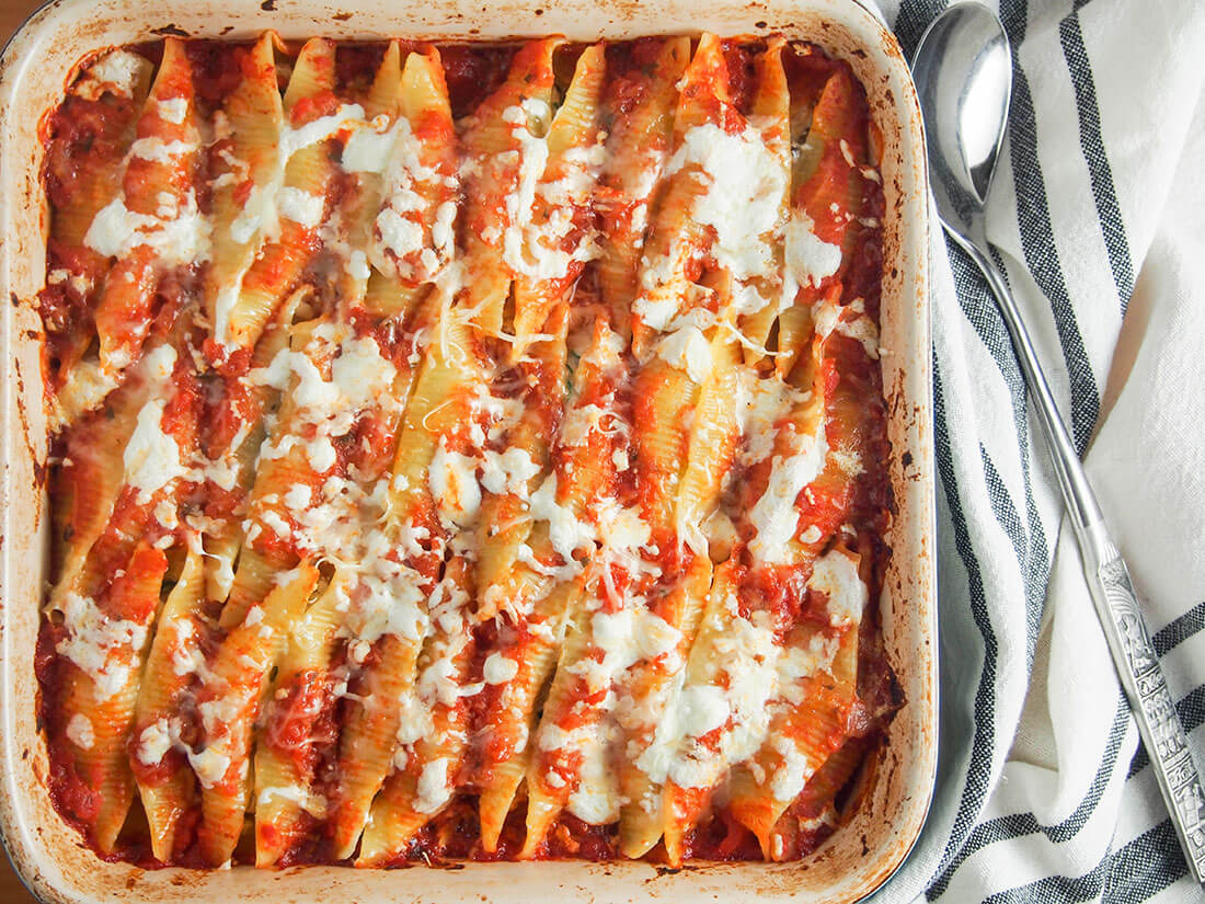 dish of pulled pork stuffed shells with serving spoon to side