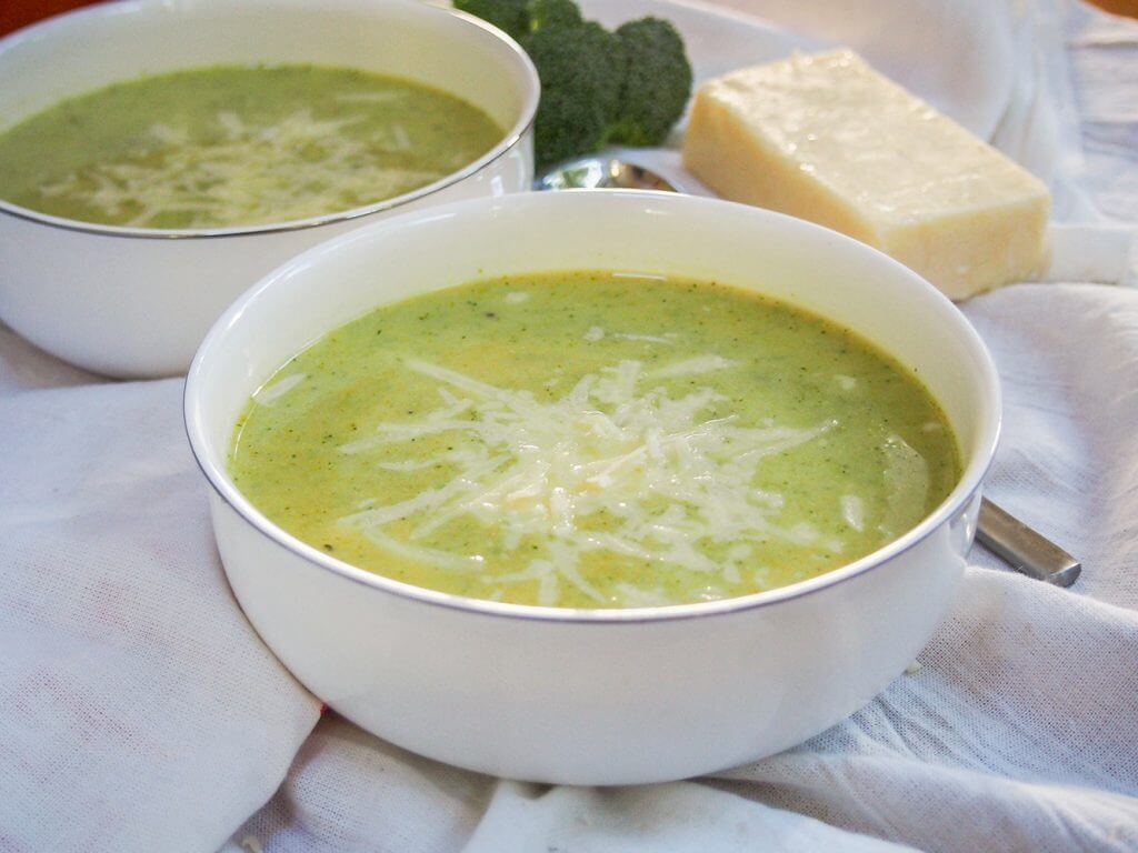 bowl of pumpkin broccoli soup with cheddar with second bowl behind