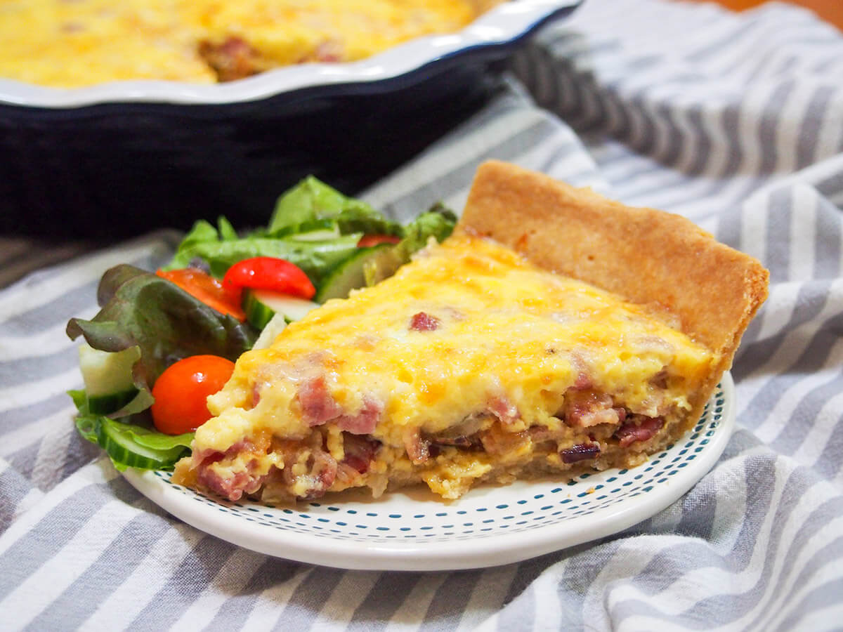 slice of quiche Lorraine with salad on plate