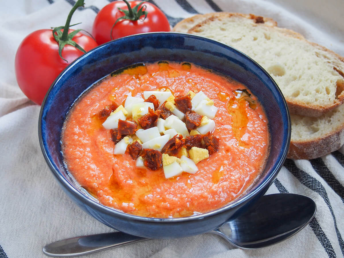 bowl of salmorejo cold tomato soup with spoon below bowl