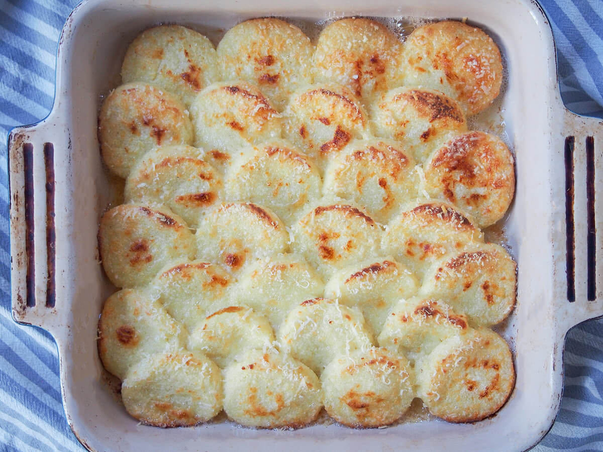 dish of semolina gnocchi, gnocchi alla Romana, from overhead with handles of dish showing either side.