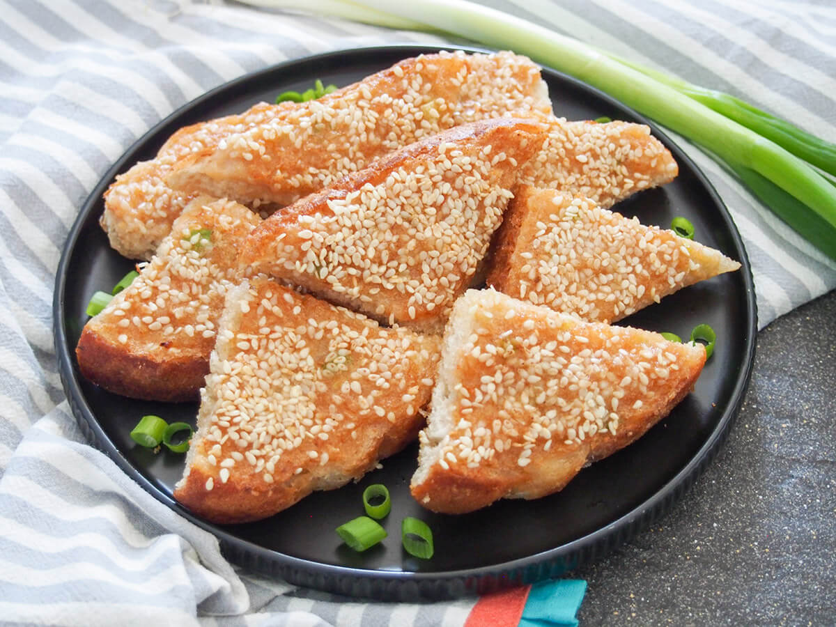 plate of sesame shrimp toast with spring onion behind