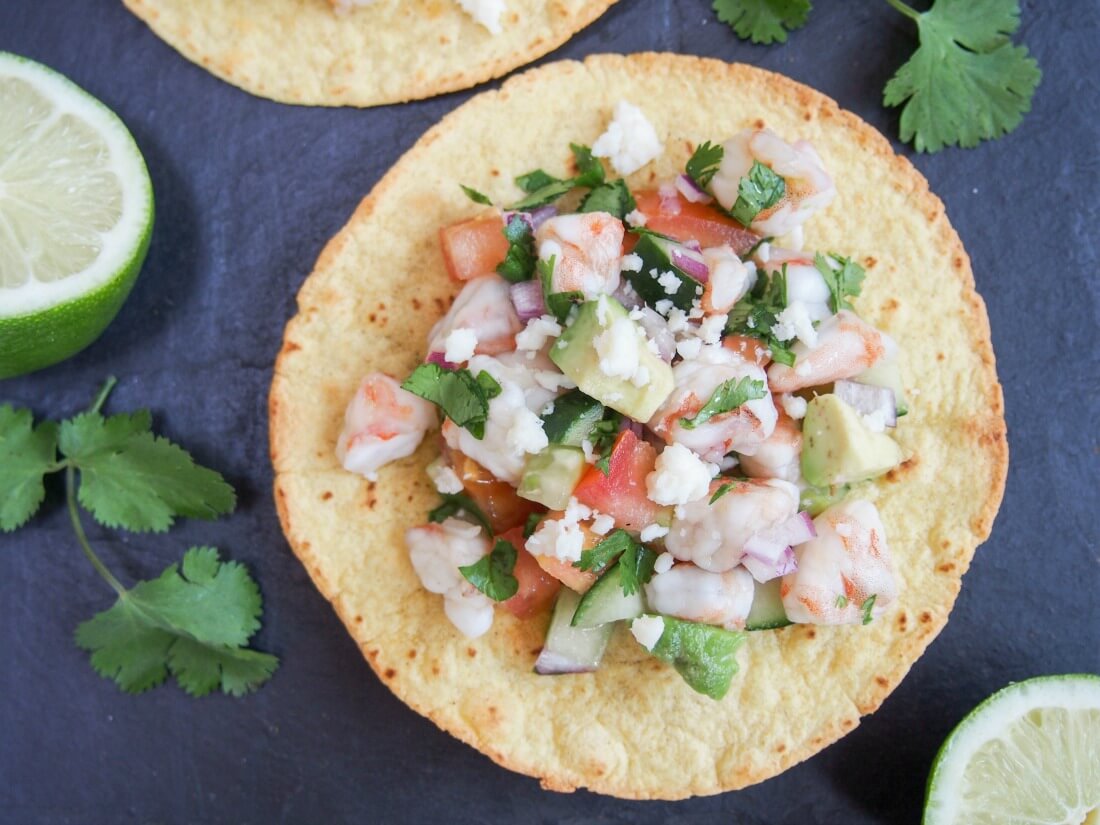 Shrimp ceviche tostada from overhead with limes to side