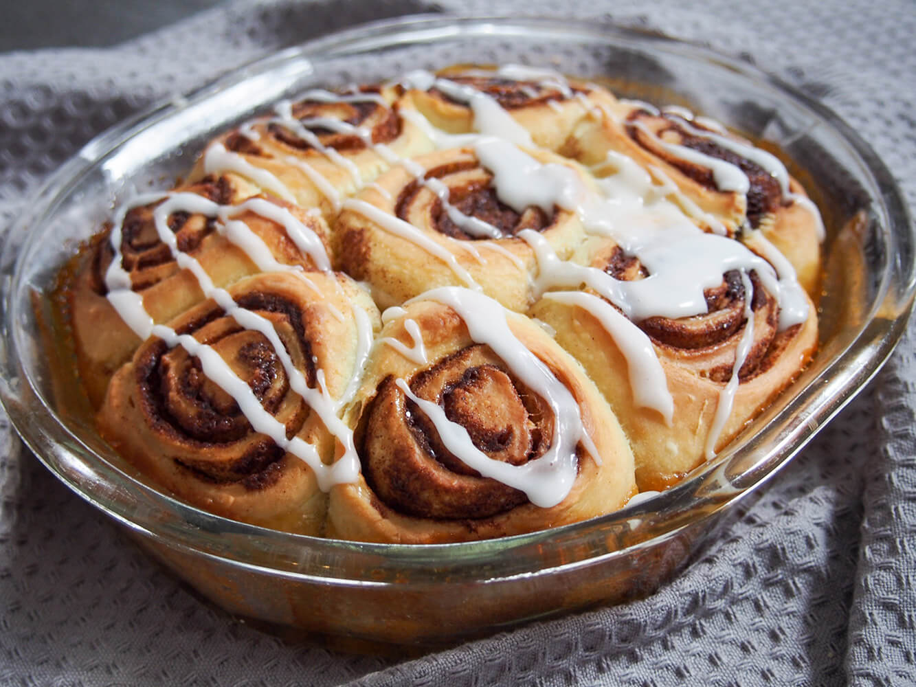 sourdough cinnamon rolls in baking dish decorated with glaze