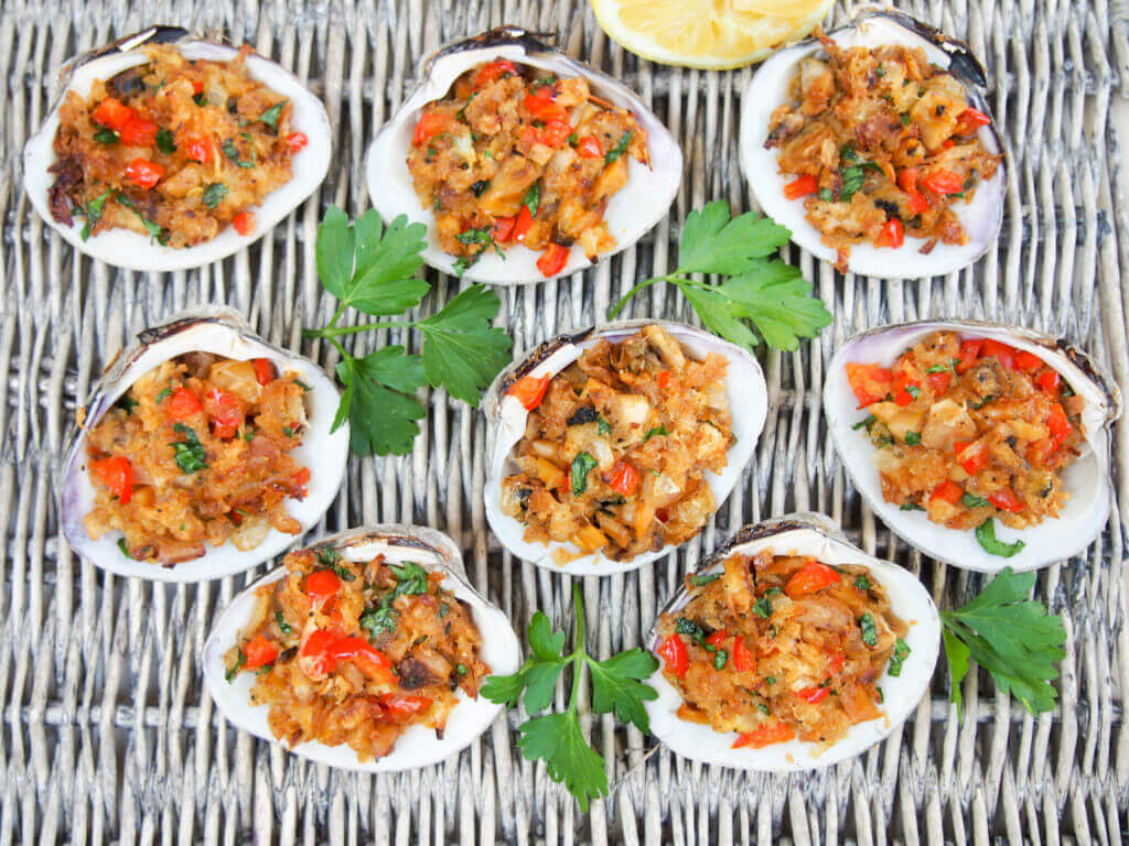 New England-style stuffed clams on basket with parsley garnish between clams