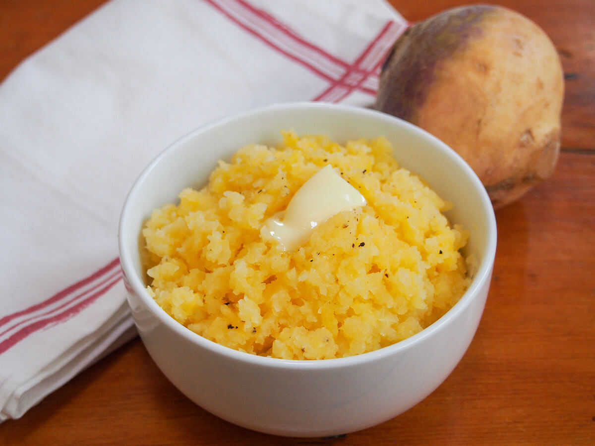 bowl of mashed rutabaga with cloth and rutabaga/swede behind