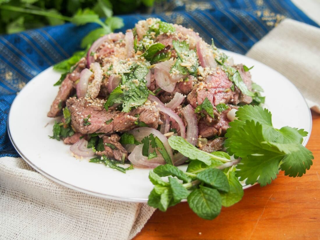 Thai beef salad (Nam Tok, 'waterfall beef') on plate decorated with herbs