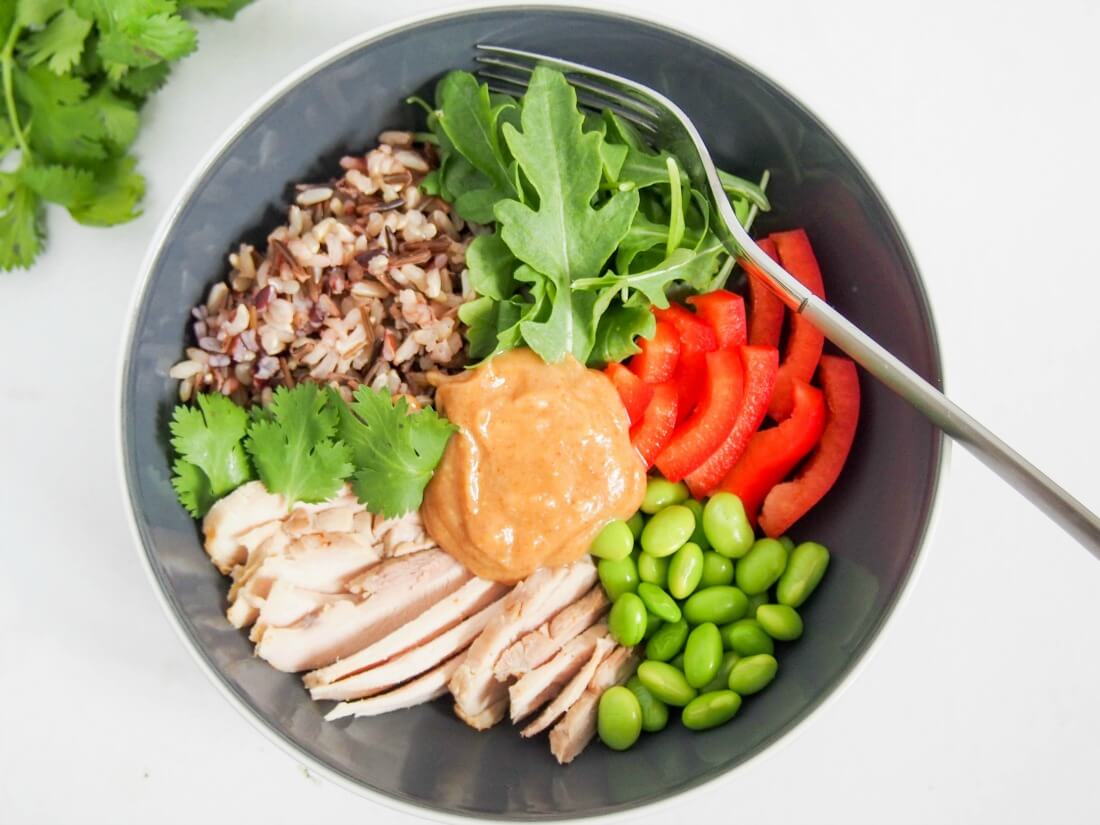 Thai-style leftover chicken Buddha bowl with fork in top of bowl from overhead