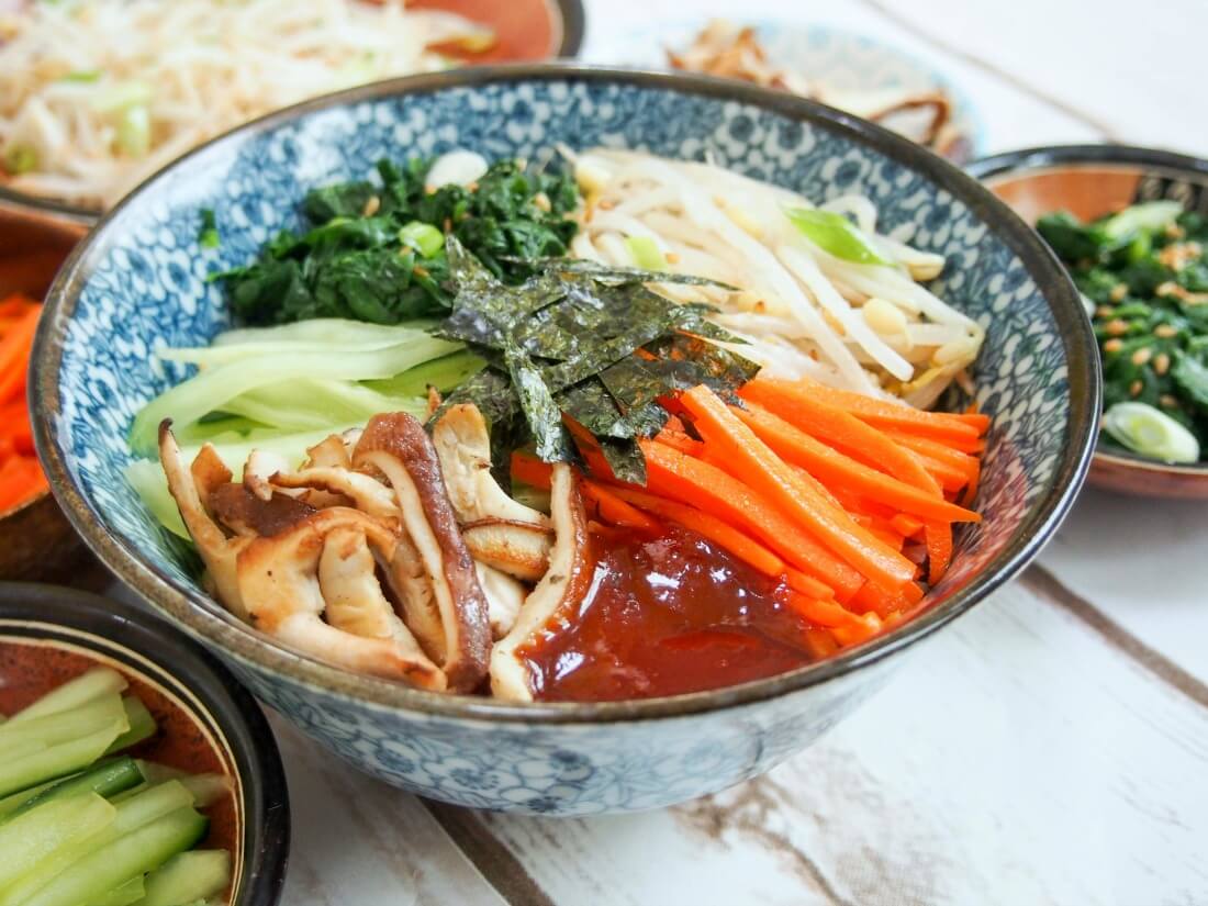 vegetarian bibimbap in bowl with vegetables in piles on top 