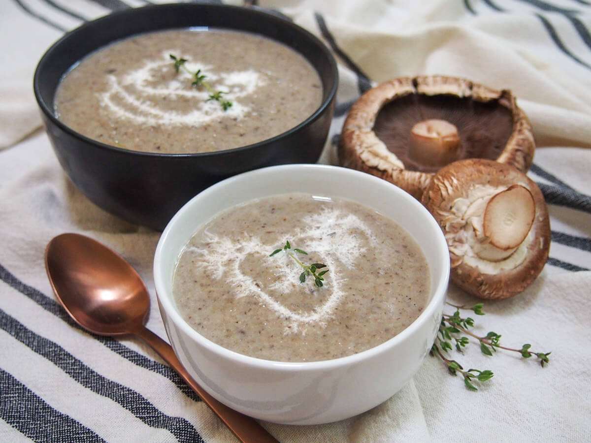 white bowl with wild mushroom soup and black bowl of soup behind